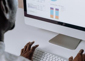 Businessman analyzing charts and data on desktop computer in office setting.
